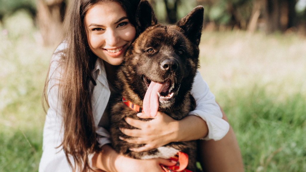 Woman hugging a dark-colored dog with a long tongue, representing a breed to avoid for autism support.