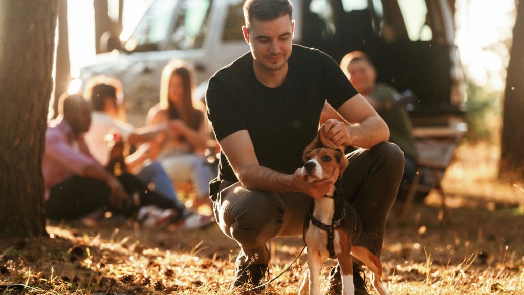 Man with a small hunting dog at a campsite.